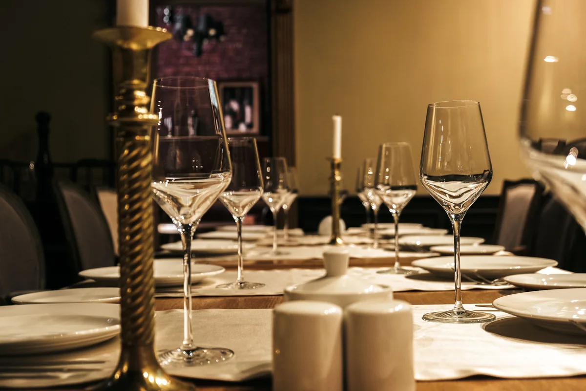 A long dinner table set with wine glasses and candlelight